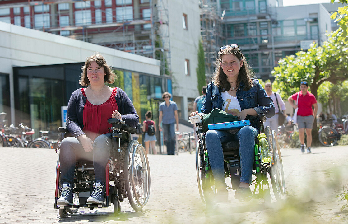 Zwei Personen in Rollstühlen