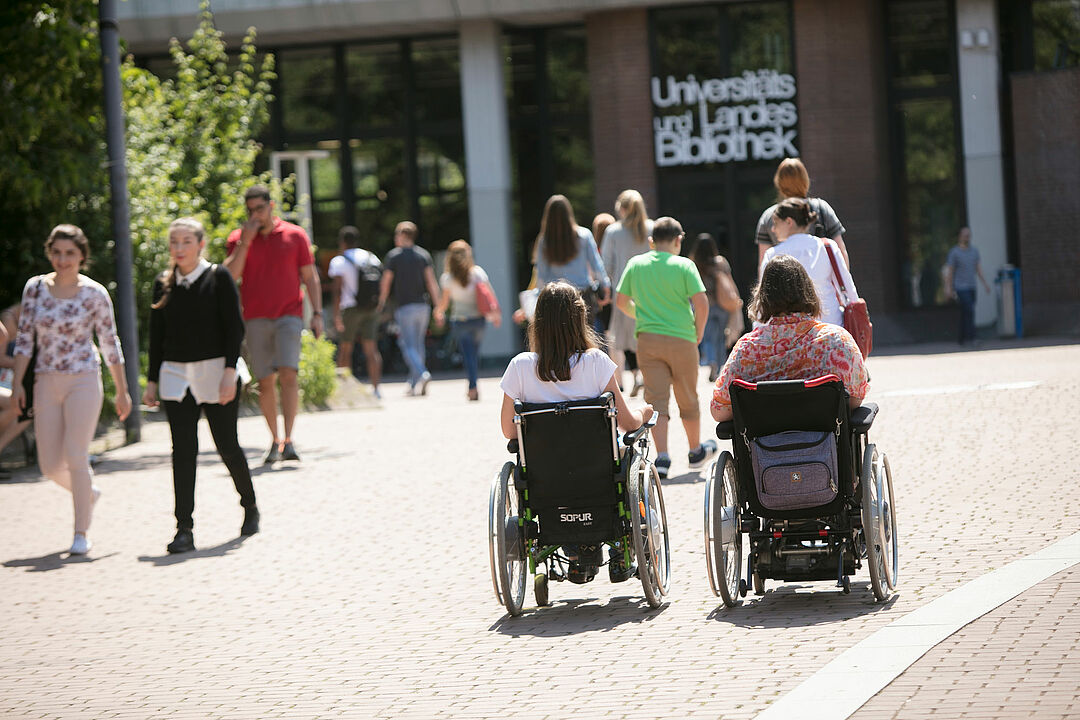 Zwei Rollstuhlfahrerinnen auf dem HHU-Campus