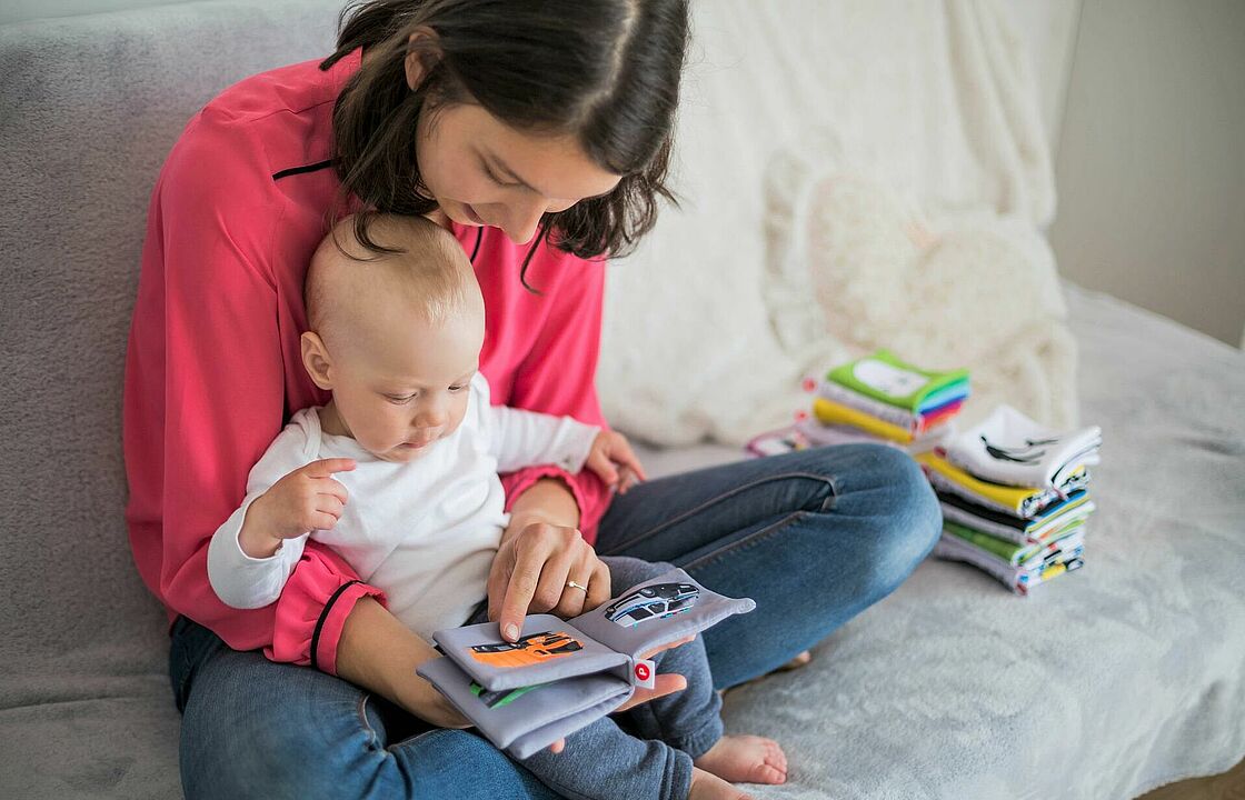 Mutter mit Kind blättert in einem Buch