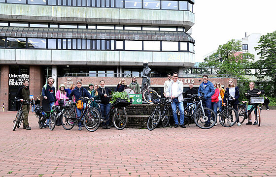 Mehrere Personen mit Fahrrädern vor der Heinestatue