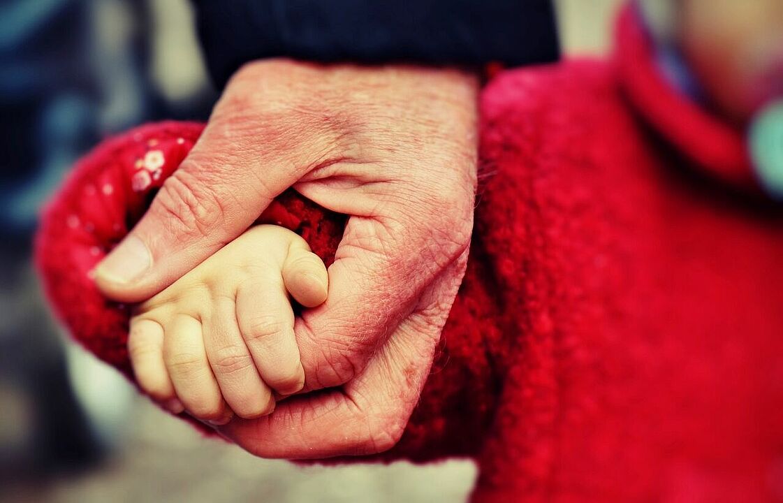 Eine Hand von einer älteren Person hält die eines Kleinkindes